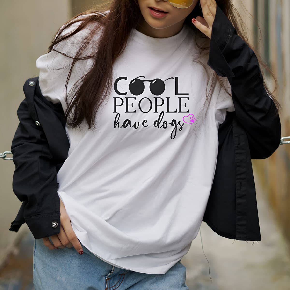 Cool Woman with sunglasses standing outside, wearing a White crew neck short sleeved t-shirt, feature a graphic ”cool people have dogs” across chest.