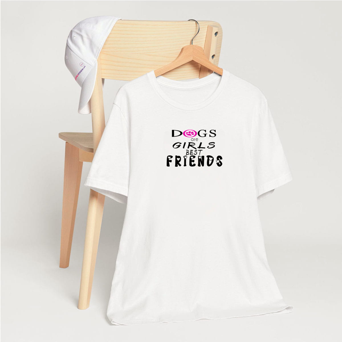White crew neck short sleeved t-shirt, feature a fun statement, quote "dogs are girls best friends". T-shirt hanging on chair shown in close-up to highlight print and size.