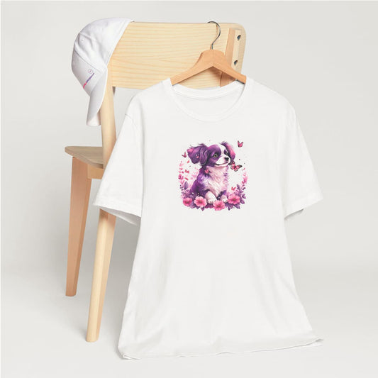 White crew neck short sleeved t-shirt, features a puppy in a wicked basket overflowing with delicate floral. T-shirt hanging on chair shown in close-up to highlight print and size