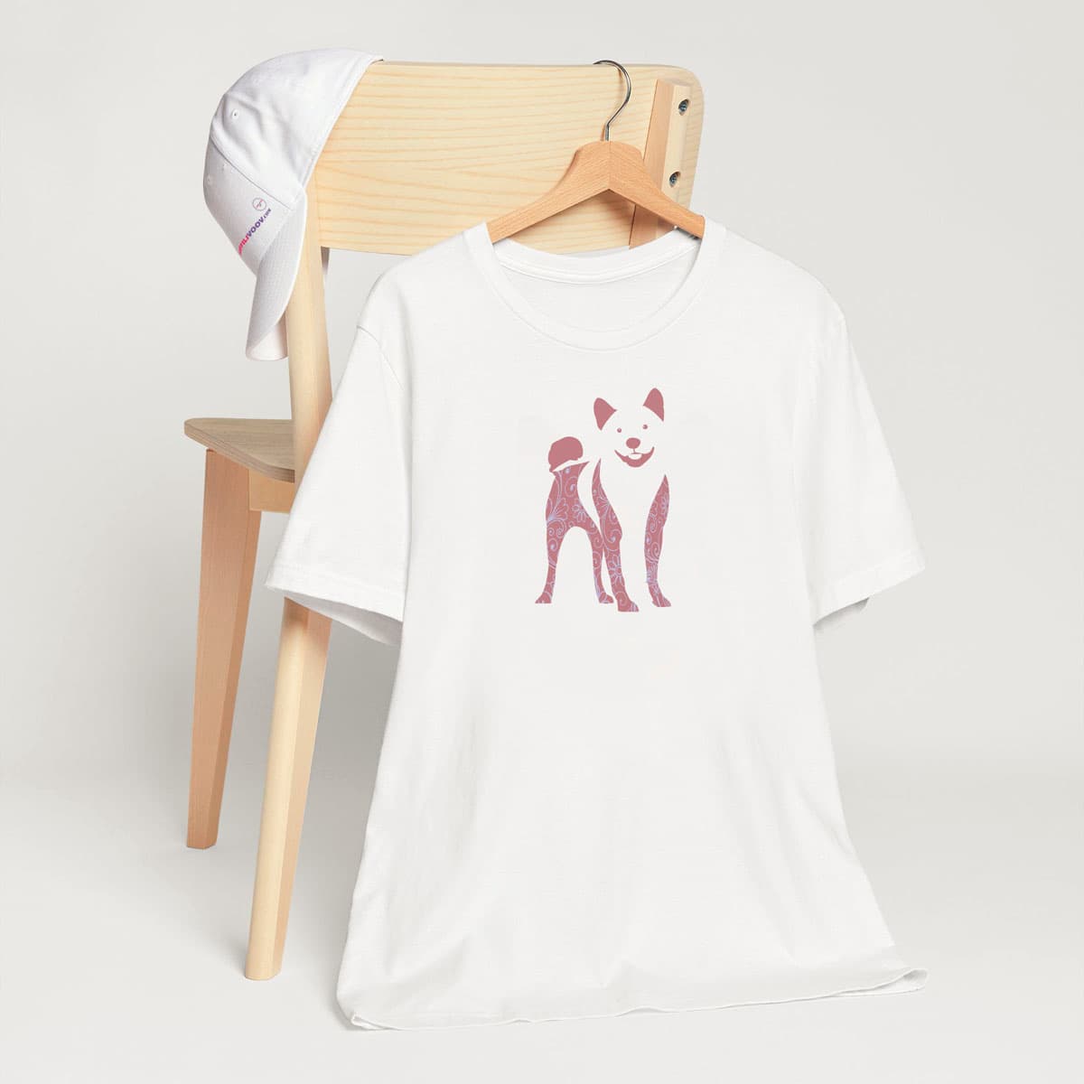 White crew neck short sleeved t-shirt. features a charming bulldog silhouette with floral and swirl pattern design. T-shirt hanging on chair shown in close-up to highlight print and size