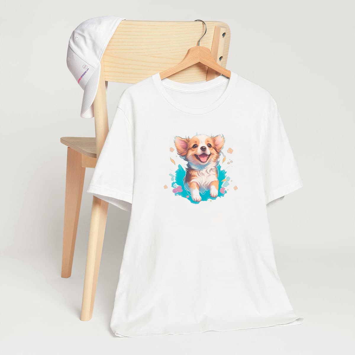 White crew neck short sleeved t-shirt, feature a happy Corgi puppy nestled in a wicker basket of vibrant blooms. and colorful design. T-shirt hanging on chair shown in close-up to highlight print and size