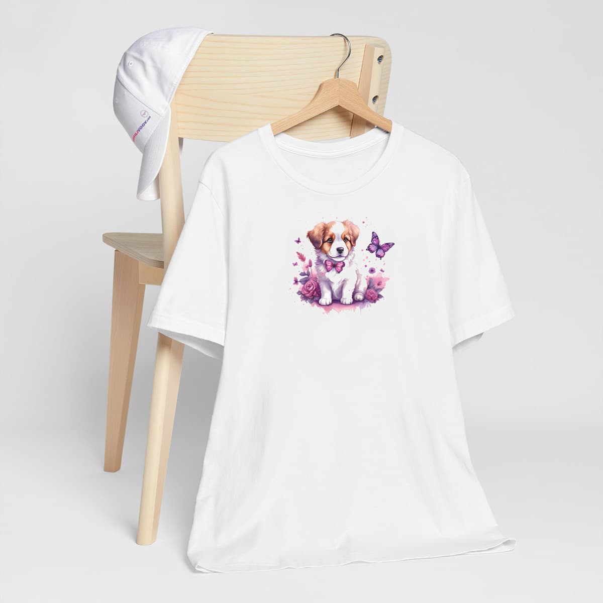 White crew neck short sleeved t-shirt, Feature an adorable puppy nestled within a vibrant floral tapestry. T-shirt hanging on chair shown in close-up to highlight print and size