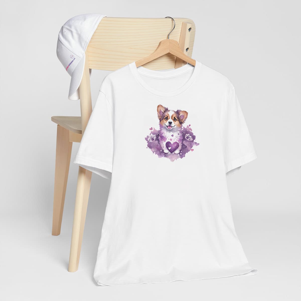 White crew neck short sleeved t-shirt, Showcasing an adorable dog puppy´s face, nestle in hearts and purple vibrant colors blooming garden. T-shirt hanging on chair shown in close-up to highlight print and size