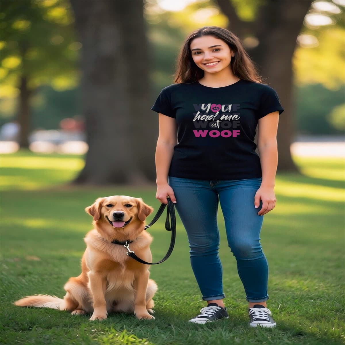 Woman sitting outside with a black dog sitting close to her, she is wearing a Black crew neck short sleeved t-shirt, feature a graphic classic quote ”you had me at woof” across chest.