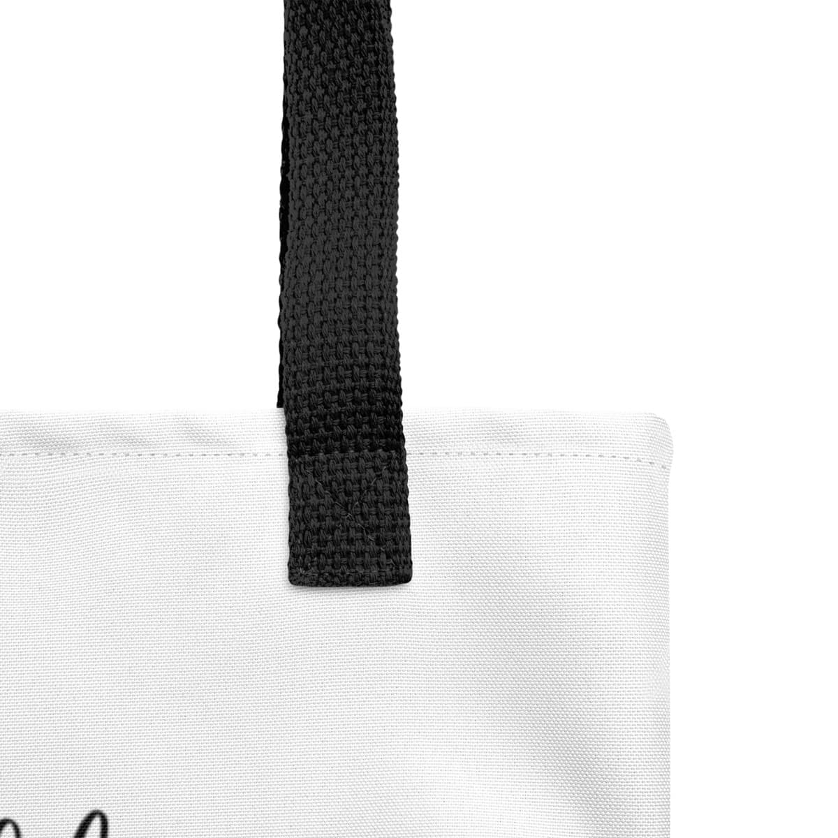 Close up of seams and stitch of a white spun canvas fabric tote bag, with black handle stripped, on the tote is graphic quote saying" dogs fill your life with joy, your heart with love and your soul with happiness"