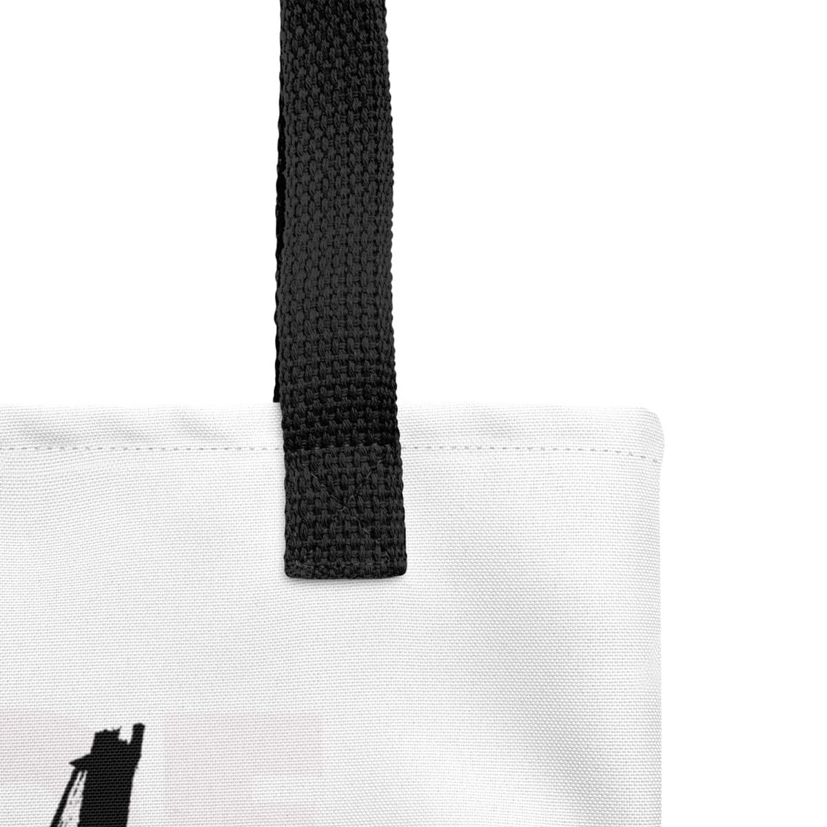 Close up of tote bag, with black stripped handle, white seams stitch aligned with white spun 100% polyester canvas fabric.