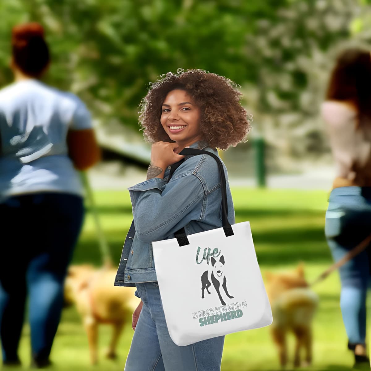 Young women standing outside in a dog park. she is wearing on her shoulder a white tote polyester canvas bag, with black stripped handle, feature a black one-line German Shepherd puppy print with life quote ”life is more fun with a Shepherd”. Printed front and back.