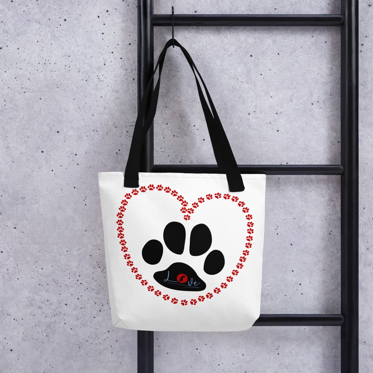 Hanging on a hook a Uni-size 15"x15" white tote polyester canvas bag, with black stripped handle, feature a black one-line large paw print, underlay by bold LOVE with a cute silhouette dog in the ”o” in red color.