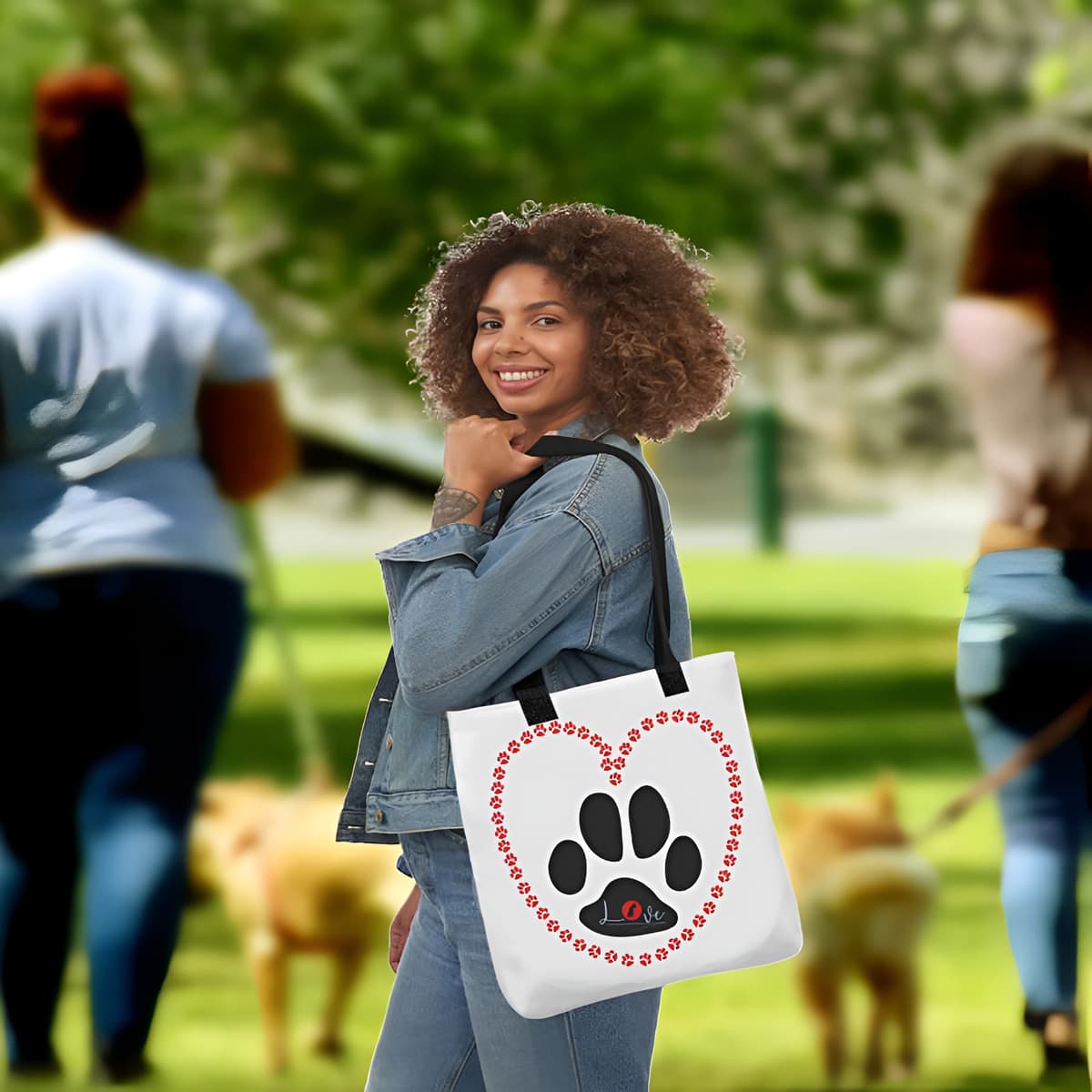 Young women standing in a park, carry on her shoulder is a white tote polyester canvas bag, with black stripped handle, feature a black one-line large paw print, underlay by bold LOVE with a cute silhouette dog in the ”o” in red color.