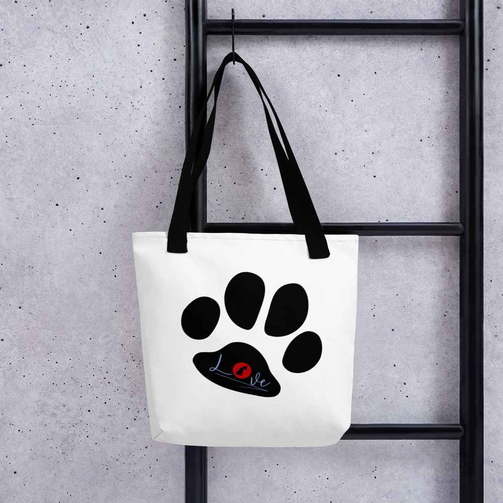 White spun canvas fabric tote bag, with black handle stripped, on the tote is cute graphic large paw, on top of the large paw is the text "love" the letter "o" in "love" is a red logo of a dog sitting