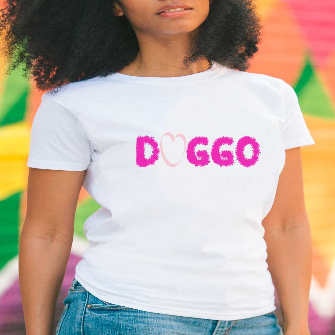 White cotton crew neck unisex short sleeve tshirt, on the apparel is a purple graphic text saying "doggo" written with fluffy outline, in the word "o" in doggo is a graphic pink shaped heart.