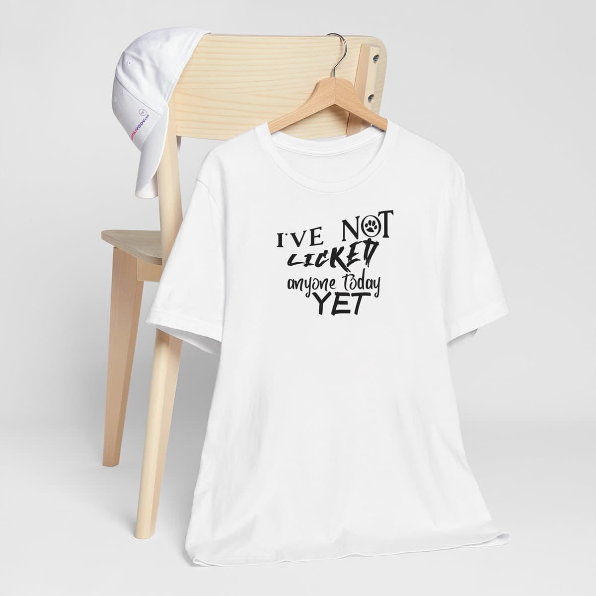 White crew neck short sleeved t-shirt, feature a funny message " I´ve not licked anyone today yet" in bold black graphic style.T-shirt hanging on chair shown in close-up to highlight print and size.