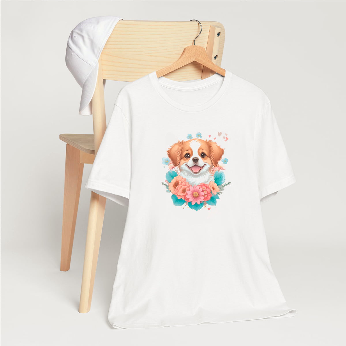 White crew neck short sleeved t-shirt, feature a graphic vibrant colorful hand-drawn dog face of a  Shepherd Puppy sitting in floral wreath. hanger on chair