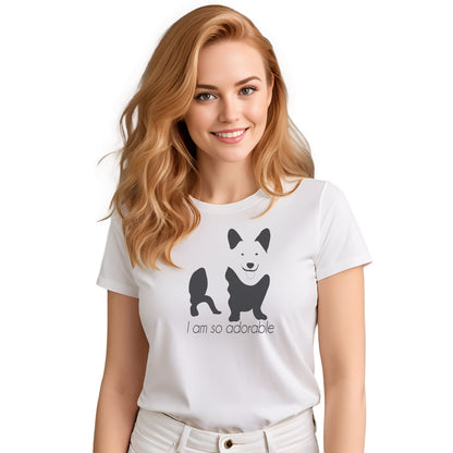 White crew neck short sleeved t-shirt, feature a graphic black/white hand-drawn corgi standing dog with quote " i am so adorable". Female model shown in close-up to highlight print and fit.
