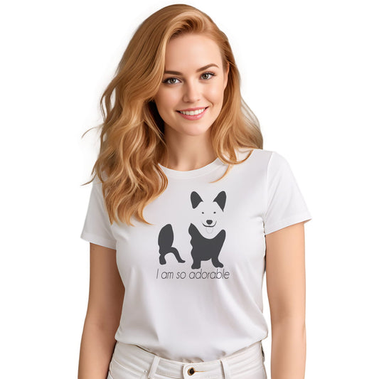 White crew neck short sleeved t-shirt, feature a graphic black/white hand-drawn corgi standing dog with quote " i am so adorable". Female model shown in close-up to highlight print and fit.
