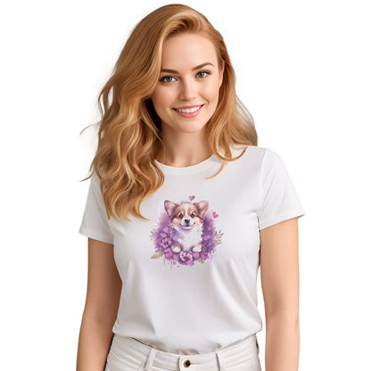 White crew neck short sleeved t-shirt, feature a graphic vibrant colorful hand-drawn Corgi puppy nestled amidst a garden of hearts and flowers in a charming wicker basket. Female model shown in close-up to highlight print and fit.