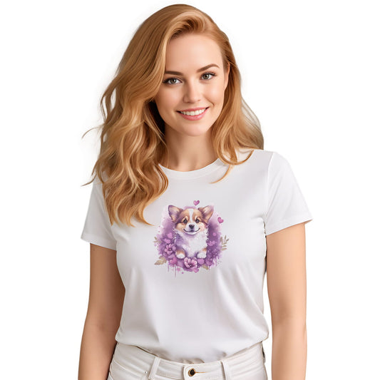 White crew neck short sleeved t-shirt, feature a graphic vibrant colorful hand-drawn Corgi puppy nestled amidst a garden of hearts and flowers in a charming wicker basket. Female model shown in close-up to highlight print and fit.