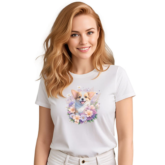 White crew neck short sleeve t-shirt with a colorful hand-drawn Corgi puppy graphic sitting in a floral garden. Close up of a Woman models the shirt, showing bold dog art, cute pet-themed fashion