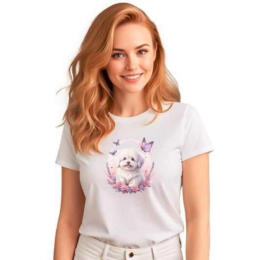 White crew neck short sleeve t-shirt with a colorful hand-drawn Coton de tulear puppy graphic sitting in a floral garden. Female model the shirt, close up showing bold dog art, cute pet-themed fashion