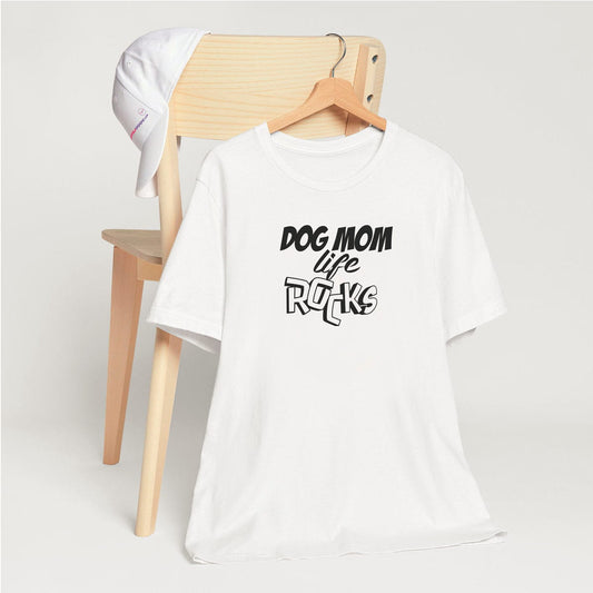 White crew neck short sleeved t-shirt, feature fun quote and statement" Dog Mom Rocks" in 3d black/white graphic. T-shirt hanging on chair shown in close-up to highlight print and size
