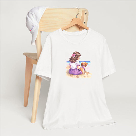White crew neck short sleeved t-shirt, boasting a lively scene of a cute puppy and a girl basking on a beach vista. T-shirt hanging on chair shown in close-up to highlight print and size
