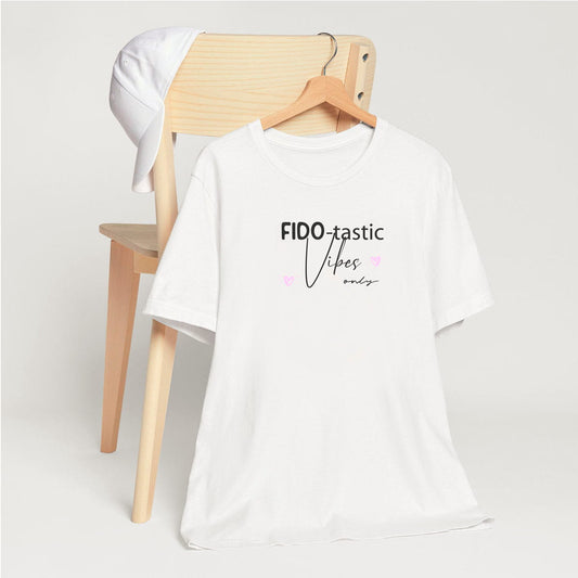 White crew neck short sleeved t-shirt, feature a fun statement, quote ”Fido-tastic Vibes Only”. T-shirt hanging on chair shown in close-up to highlight print and size