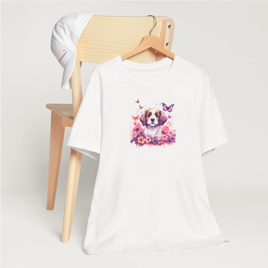 White crew neck short sleeved t-shirt, featuring an utterly charming puppy nestled amidst a blooming floral spectacle within a wicker basket. T-shirt hanging on chair shown in close-up to highlight print and size