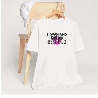 White crew neck short sleeved t-shirt, features a playful message "Hoomans call me best bud" with humorist twist, underlined by a pink dog paw.T-shirt hanging on chair shown in close-up to highlight print and size