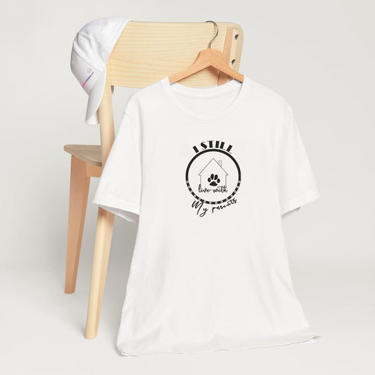 White crew neck short sleeved t-shirt, showcases a cartoon hand-drawn house with a dog paw, circled by the funny quote "I still live with my parents. T-shirt hanging on chair shown in close-up to highlight print and size