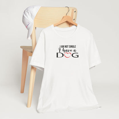 White crew neck short sleeved t-shirt. Showcases with humor a text saying "I am not single I have a dog". T-shirt hanging on chair shown in close-up to highlight print and size
