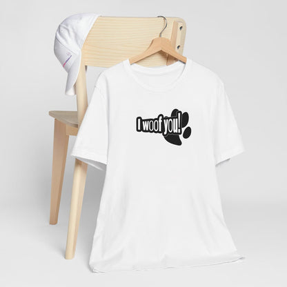 White crew neck short sleeved t-shirt, feature a funny message "I woof you" designed in a cartoonist way, underlined by a dog paw. T-shirt hanging on chair shown in close-up to highlight print and size.