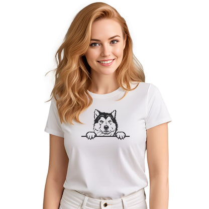 White crew neck short sleeved t-shirt. Showcase an adorable black/white hand-drawn graphic Malamute dog face resting on a table. Female model shown in close-up to highlight print and fit.
