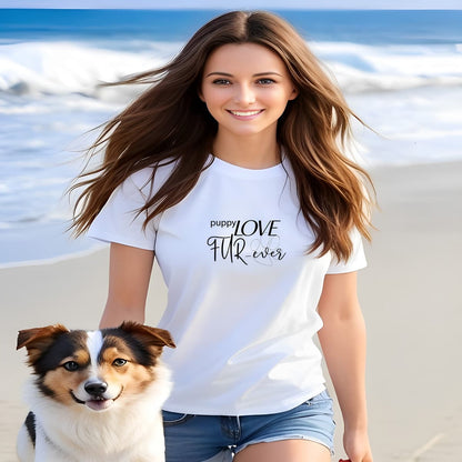 Women walking at a beach with a dog. She is wearing a white crew neck short sleeved t-shirt, feature a message "puppy love fur-ever" underlined with a dog pawe