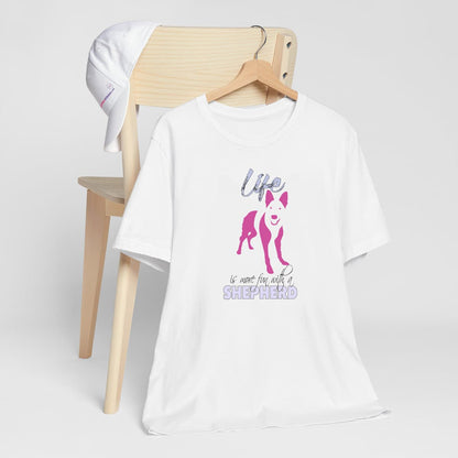 White crew neck short sleeved t-shirt. Feature a cute German Shepherd puppy silhouette with a fun message "life is more fun with a Shepherd"in pink and purple shades.T-shirt hanging on chair shown in close-up to highlight print and size.