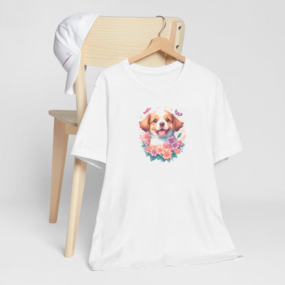 White crew neck short sleeved t-shirt, feature an intricate colorful hand-drawn lively shepherd puppy amidst a blooming wicker floral basket garden. T-shirt hanging on chair shown in close-up to highlight print and size
