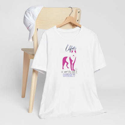 White crew neck short sleeved t-shirt. Featuring an adorable Siberian Husky silhouette in cute pink, the tee also boasts a bold "Life" message and empowering "is more fun with a Husky" phrase.T-shirt hanging on chair shown in close-up to highlight print and size