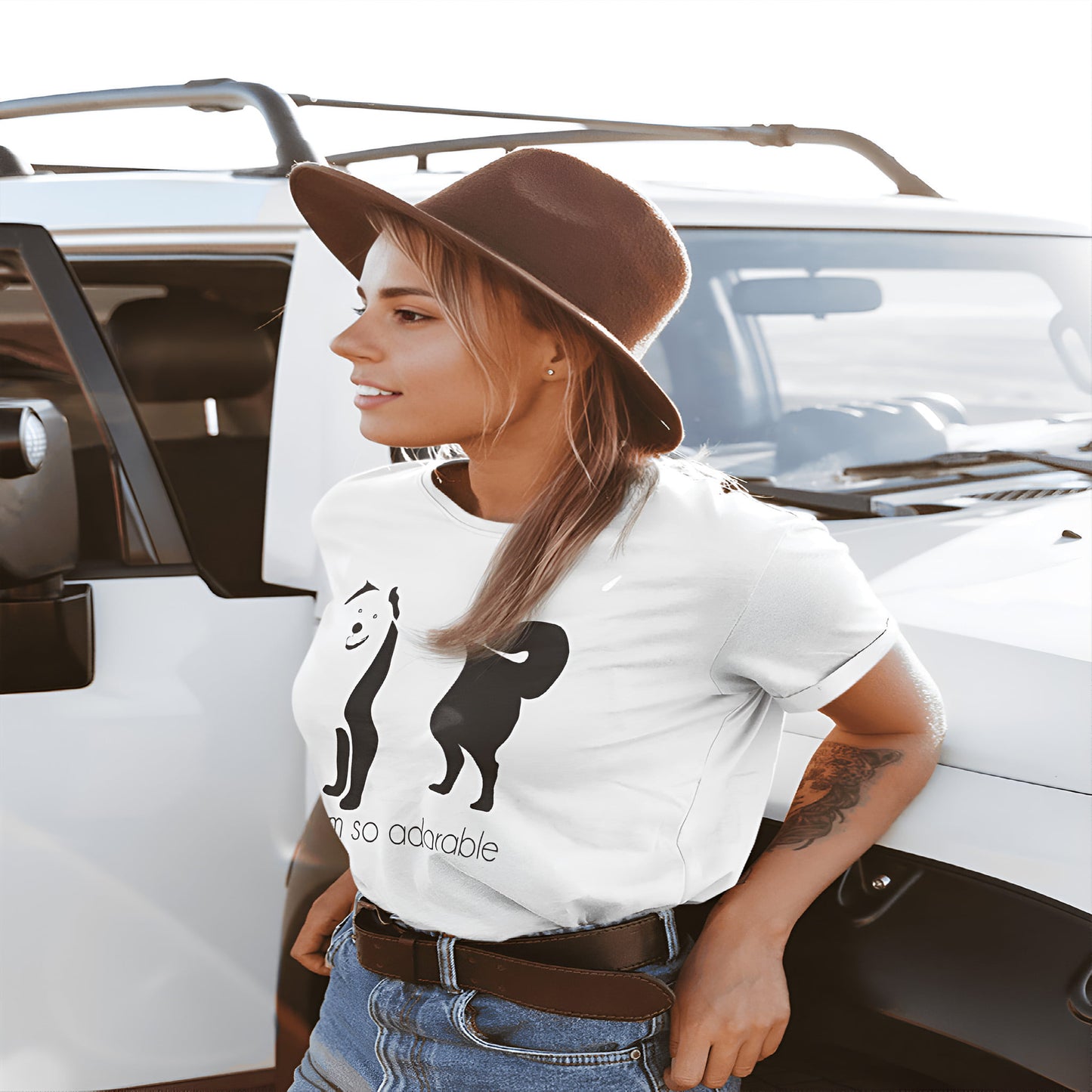Women leaning up against a truck, wearing a white crew neck short sleeved t-shirt, featuring an adorable Australian Shepherd hand drawn silhouette graphic print with the text "I am so adorable."  underneath the dog.