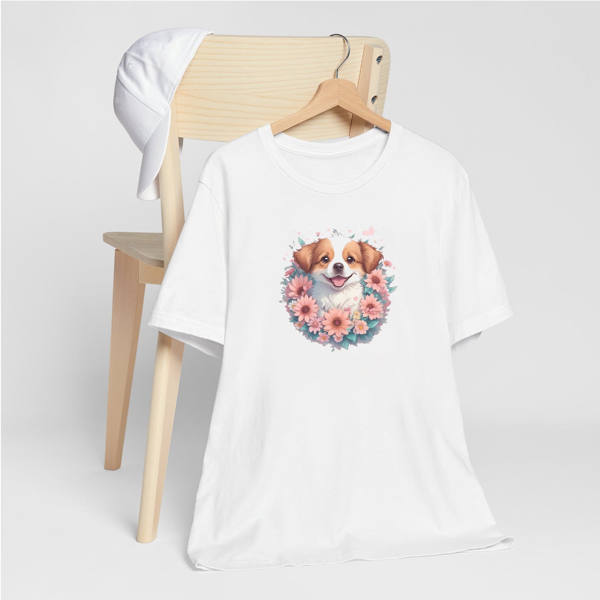White crew neck short sleeved t-shirt, feature a graphic vibrant colorful hand-drawn dog face of a  Shepherd Puppy sitting in floral wreath. T-shirt hanging on chair shown in close-up to highlight print and size.