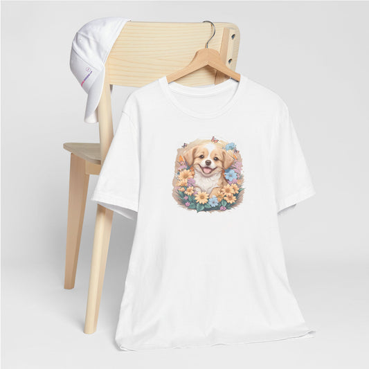 White crew neck short sleeved t-shirt, feature a graphic vibrant colorful hand-drawn dog face of a  Cavalier King Charles spaniel Puppy sitting in floral wreath. T-shirt hanging on chair shown in close-up to highlight print and size