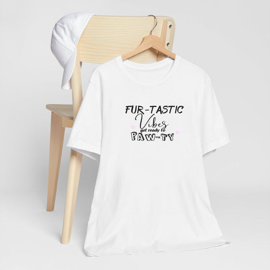 White crew neck short sleeved t-shirt, features a fun message "fur-tastic vibes get ready to paw-ty black graphic with cute pink hearts. T-shirt hanging on chair shown in close-up to highlight print and size