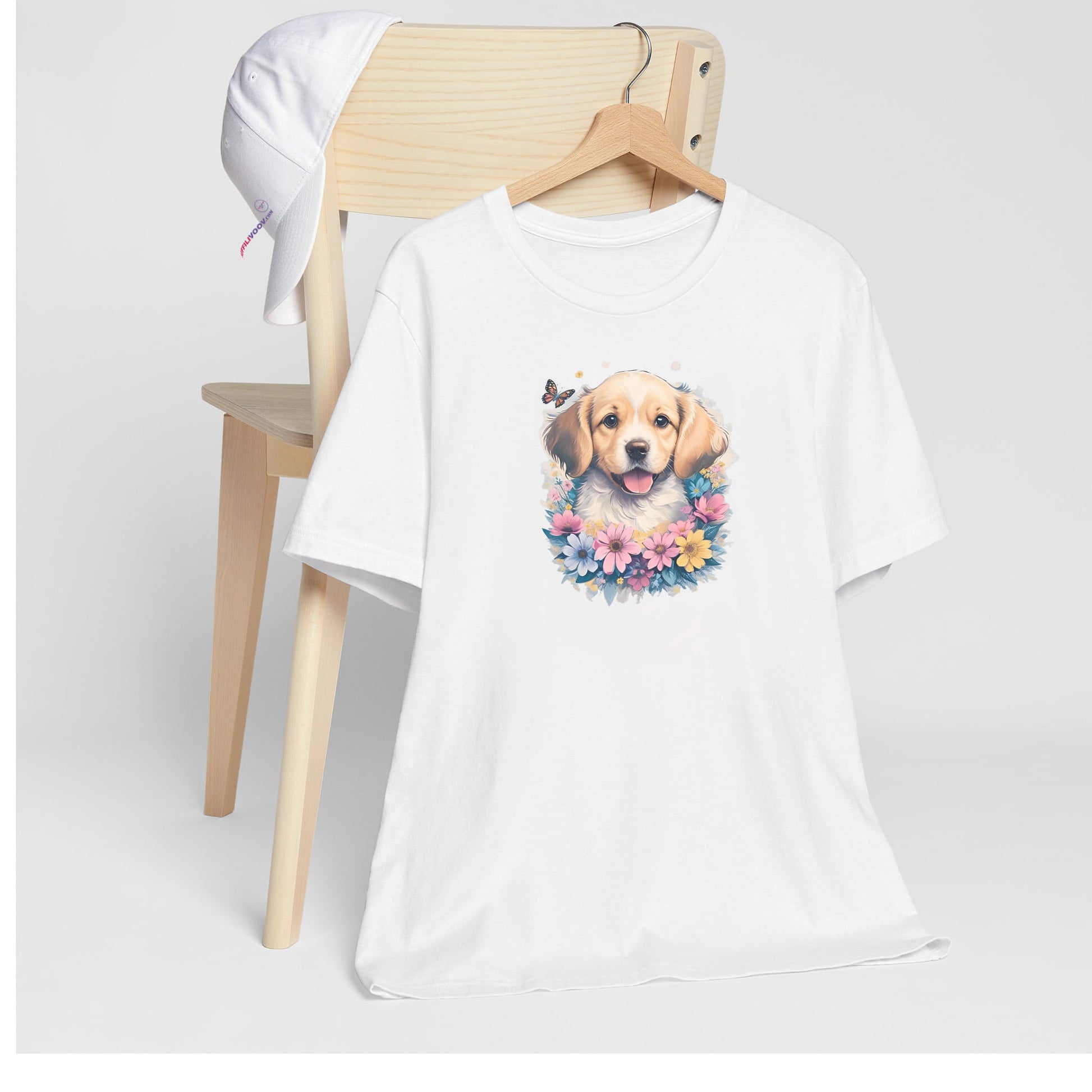 White crew neck short sleeved t-shirt, feature a cute happy Golden Retriever puppy dog face, in a nestle of butterflies and floral wreath. T-shirt hanging on chair shown in close-up to highlight print and size.
