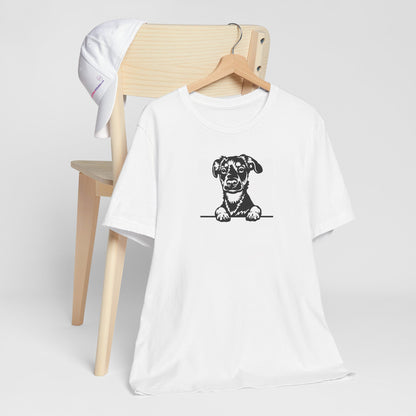 White crew neck short sleeved t-shirt. Featuring a black and white hand-drawn one-line graphic adorable Rottweiler puppy dog face, resting its paws on a table. T-shirt hanging on chair shown in close-up to highlight print and size