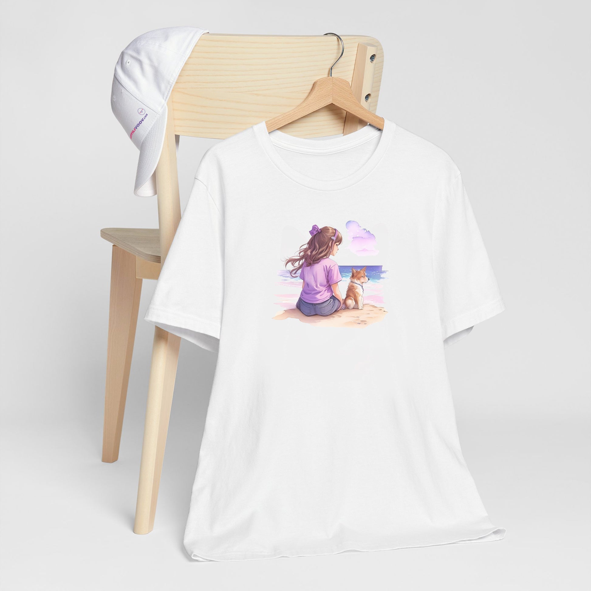 hite crew neck short sleeved t-shirt, featuring a vivid hand-drawn puppy and a girl sharing a moment on a beach, surrounded by dark reds, purples, and pinks on a pristine white background. T-shirt hanging on chair shown in close-up to highlight print and size
