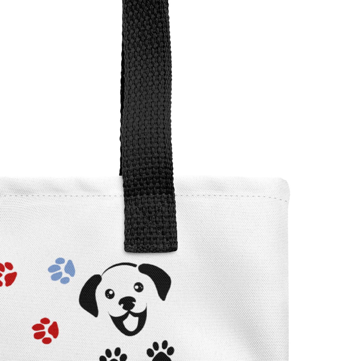 Close up of seams and stitch for a white spun canvas fabric tote bag, with black handle stripped, on the tote is a cute graphic cartoonist happy puppy face, surrounded by colorful paws.