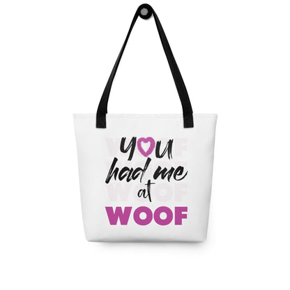 Unisize 15"x15" white tote bag, with black stripped handle, feature a classic quote you had me at woof, the letter o, is a pink colred heart with dog paw, there is underlay of thentext woof, repeated several times. Printed front and back.