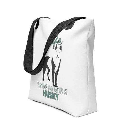 White spun canvas fabric tote bag , on the bag is a black one-line graphic print silhouette of a cute Siberian Husky dog standing with its tongue out. Above the dog is the text " LIFE" in cap and underneath the dog is the text " is more fun with a Husky " in cap