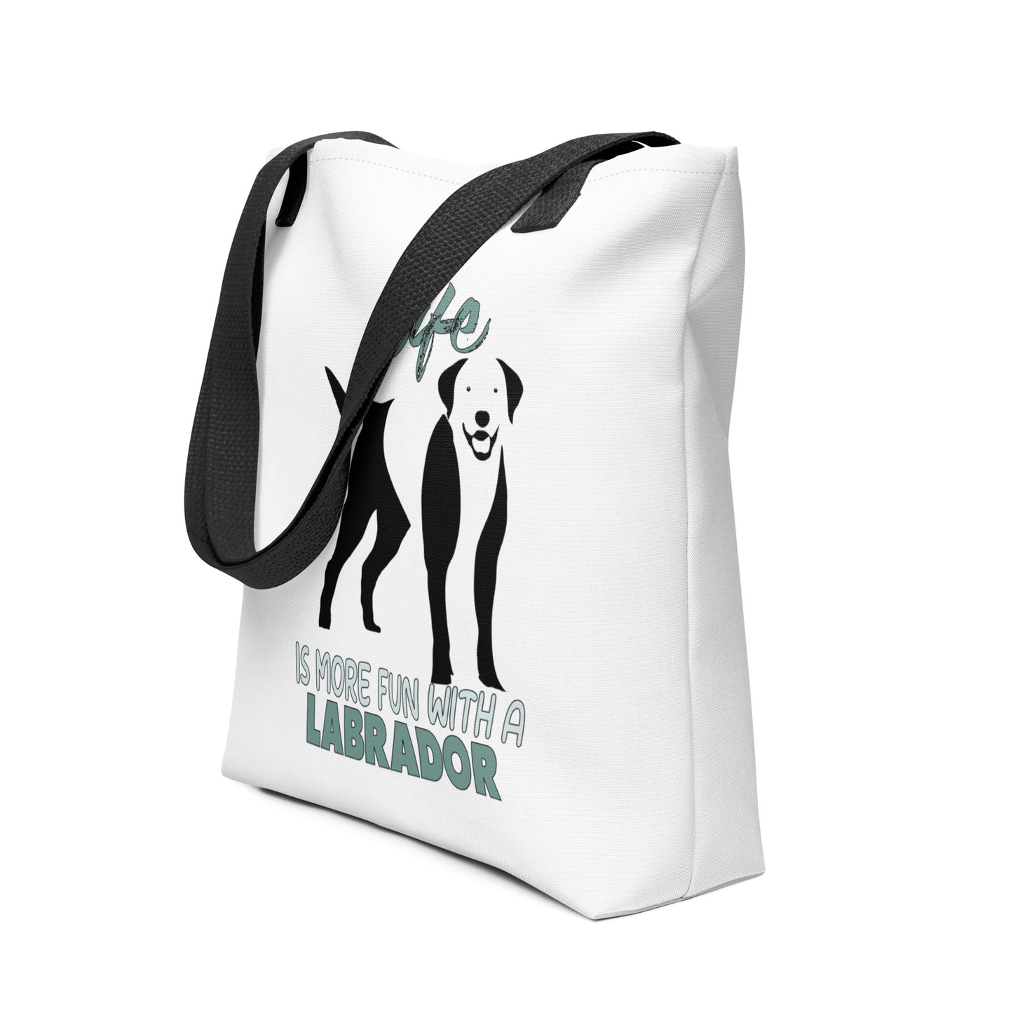 White spun canvas fabric tote bag , on the bag is a black one-line graphic print silhouette of a cute Labrador dog standing with its tongue out. Above the dog is the text " LIFE" in cap and underneath the dog is the text " is more fun with a Labrador " in cap" 