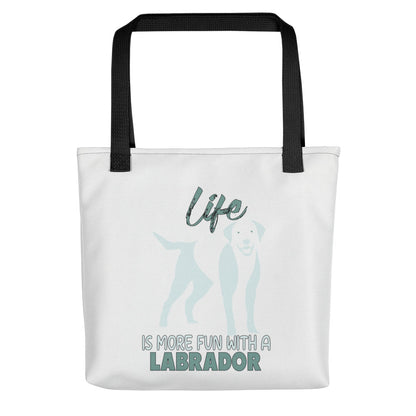 White spun canvas fabric tote bag , on the bag is a black one-line graphic print silhouette of a cute Labrador dog standing with its tongue out. Above the dog is the text " LIFE" in cap and underneath the dog is the text " is more fun with a Labrador " in cap" 