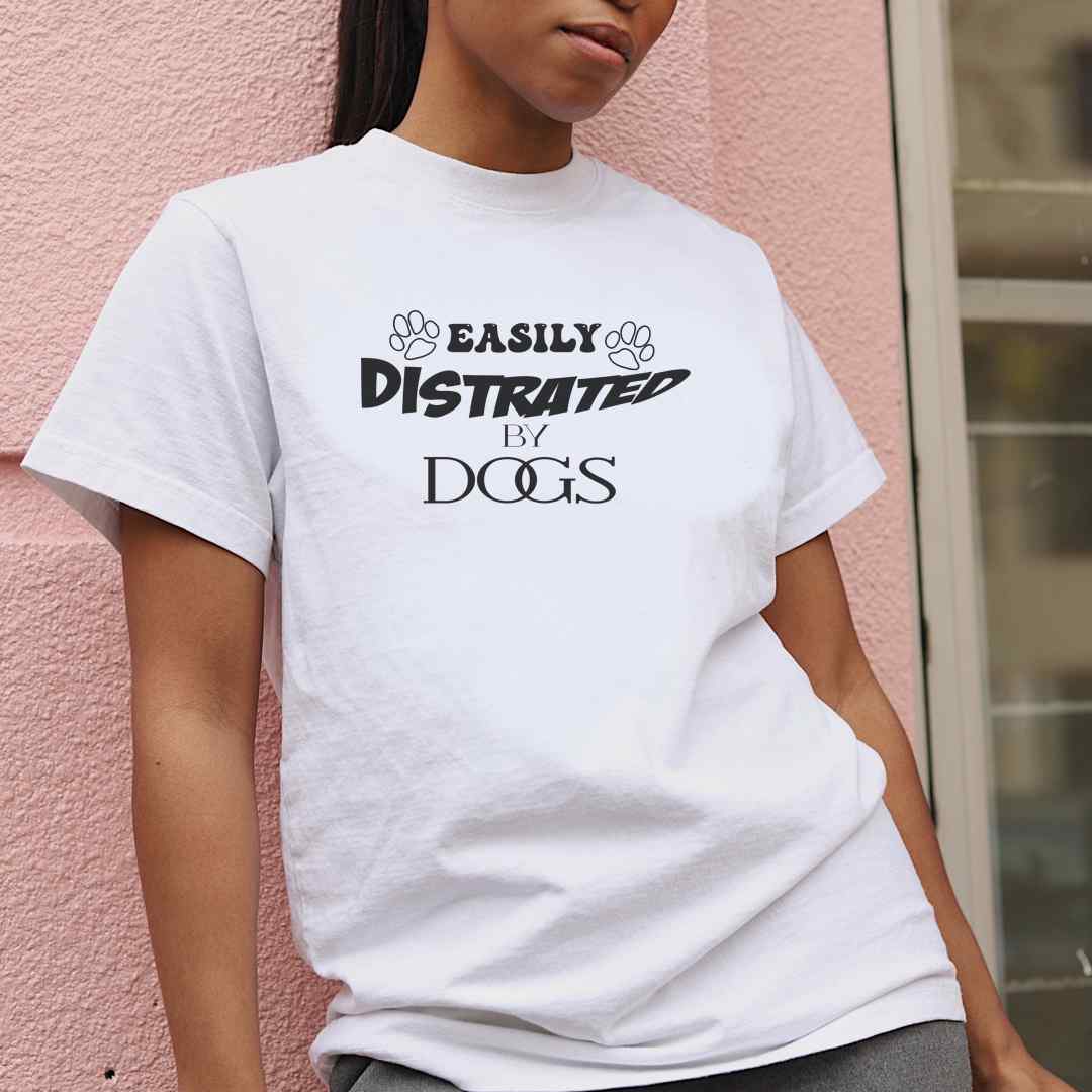 White cotton crew neck unisex  short sleeve tshirt, on the apparel is a graphic black/white text  saying "Easily distracted by dogs"  the letter Easily got two paws on the side.