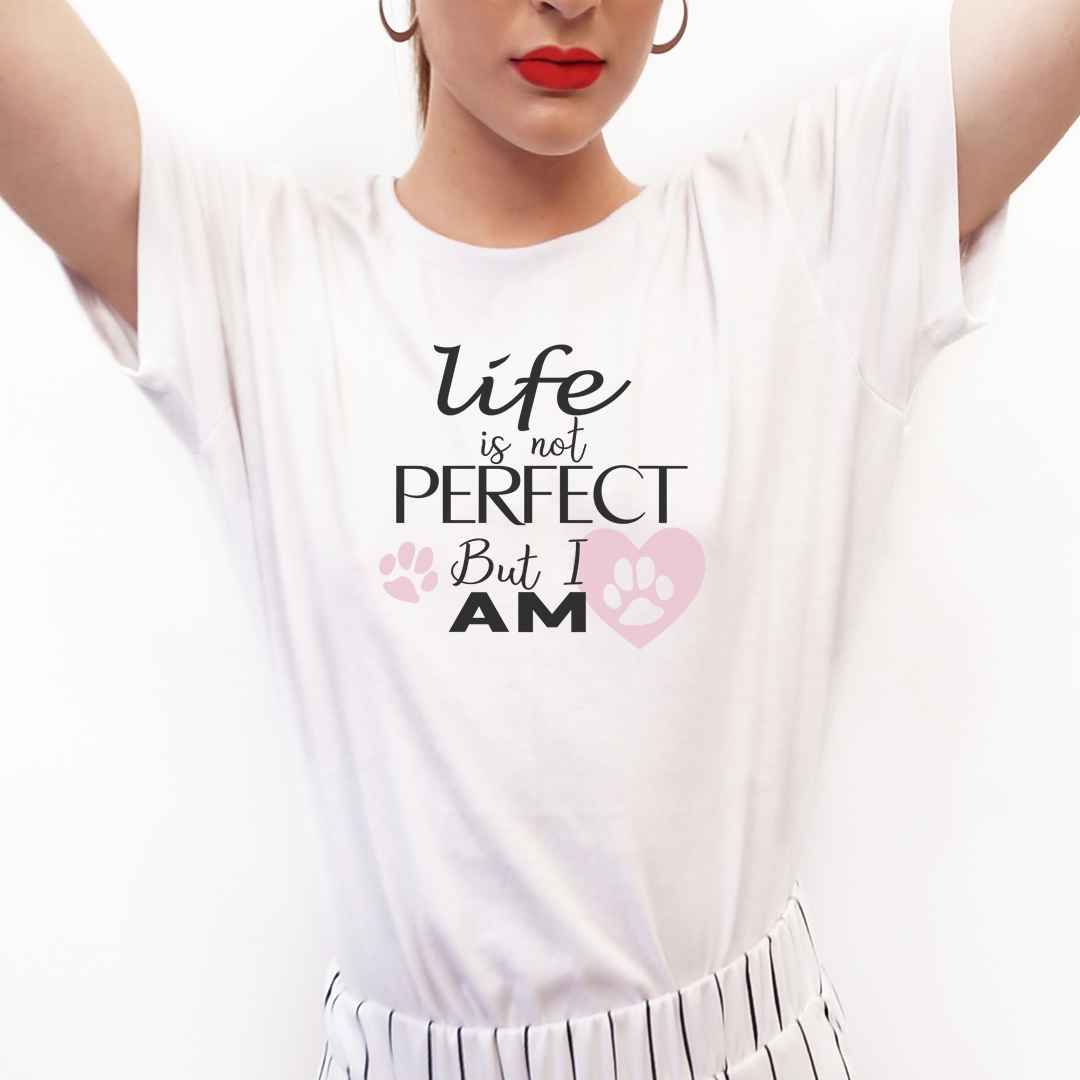 White cotton crew neck unisex  short sleeve tshirt, on the apparel is a graphic shaped pink heart with a paw inside, and another pink paw, overlayed by the text  saying " life is not perfect but i am"